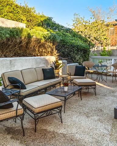 Spacious patio with iron sofa set, coffee table, and garden greenery on a sunny afternoon