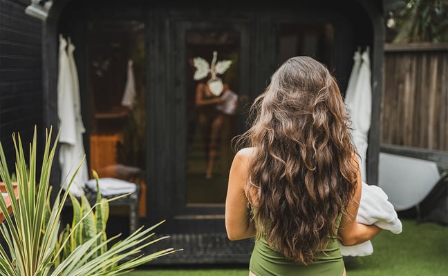 Woman walking into outdoor spa space with beautiful landscaping